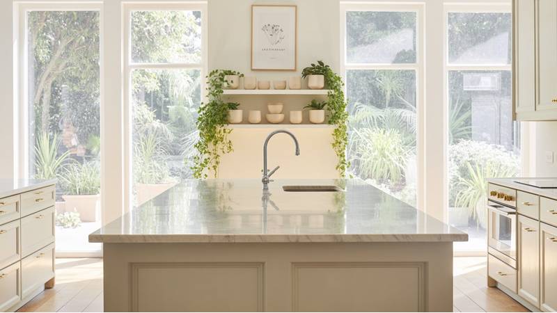 A beautifully styled kitchen with large windows, indoor plants, and soft natural light showcasing modern decor — perfect for light and airy kitchen ideas
