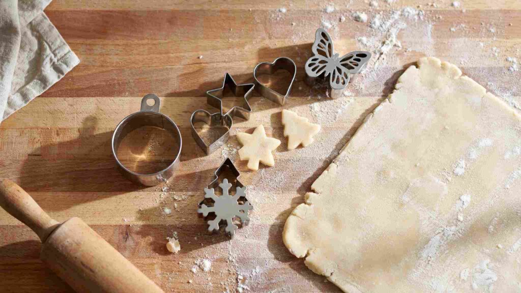 Star, heart, and round sugar cookies cooling on a wire rack after being cut with different cookie cutter shapes.