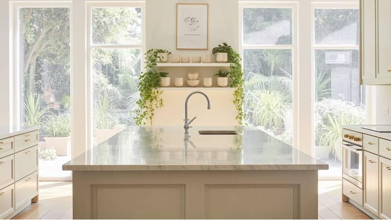 A beautifully styled kitchen with large windows, indoor plants, and soft natural light showcasing modern decor — perfect for light and airy kitchen ideas