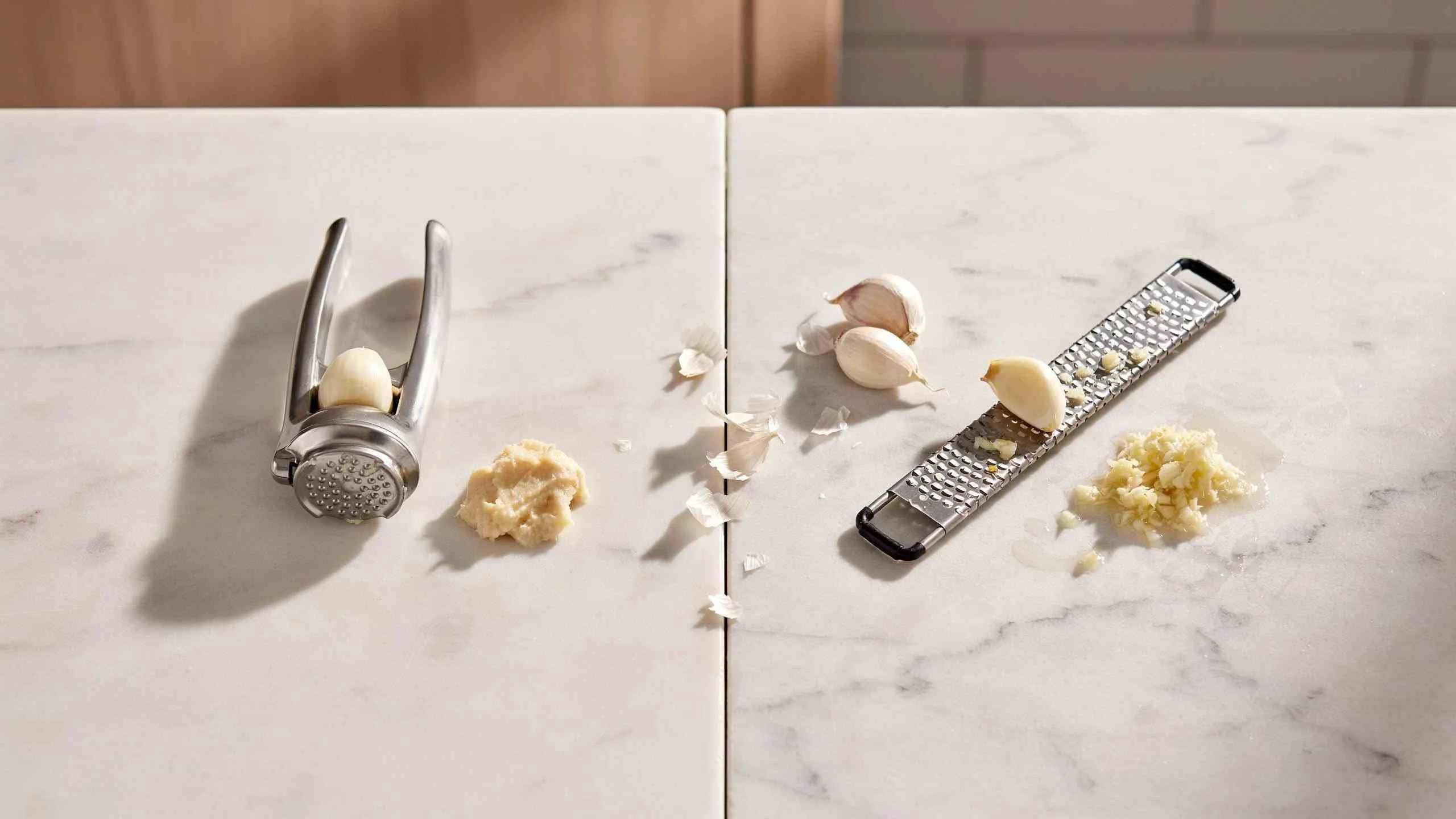 Garlic press vs garlic grater side by side, showing chunky pressed garlic paste next to finer, wetter grated garlic paste